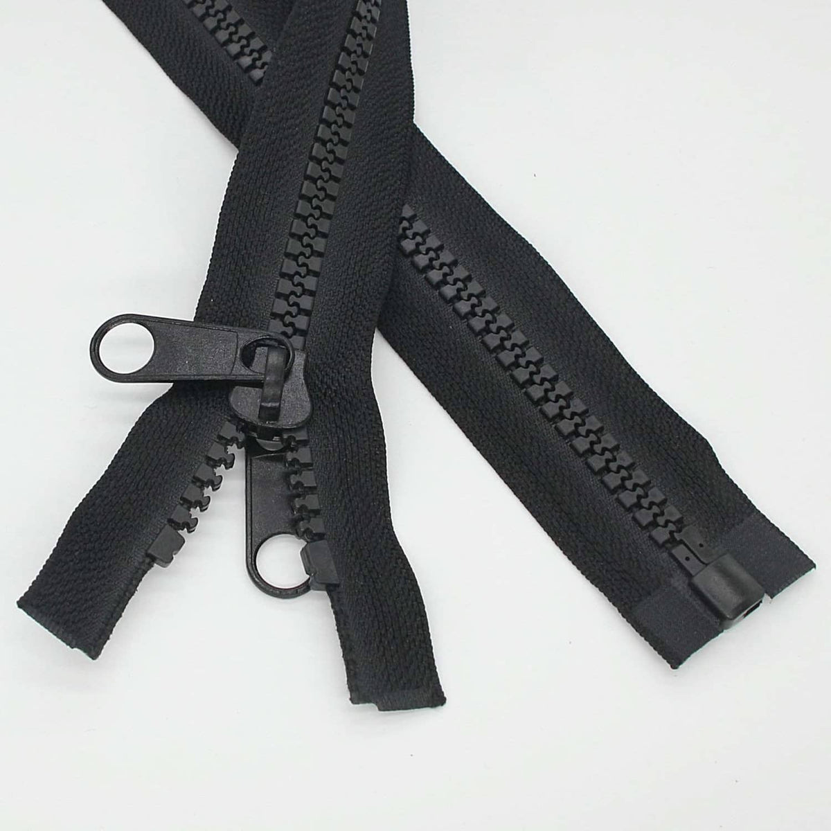 Black plastic separating zipper with double pull tabs and slider, partial length shown