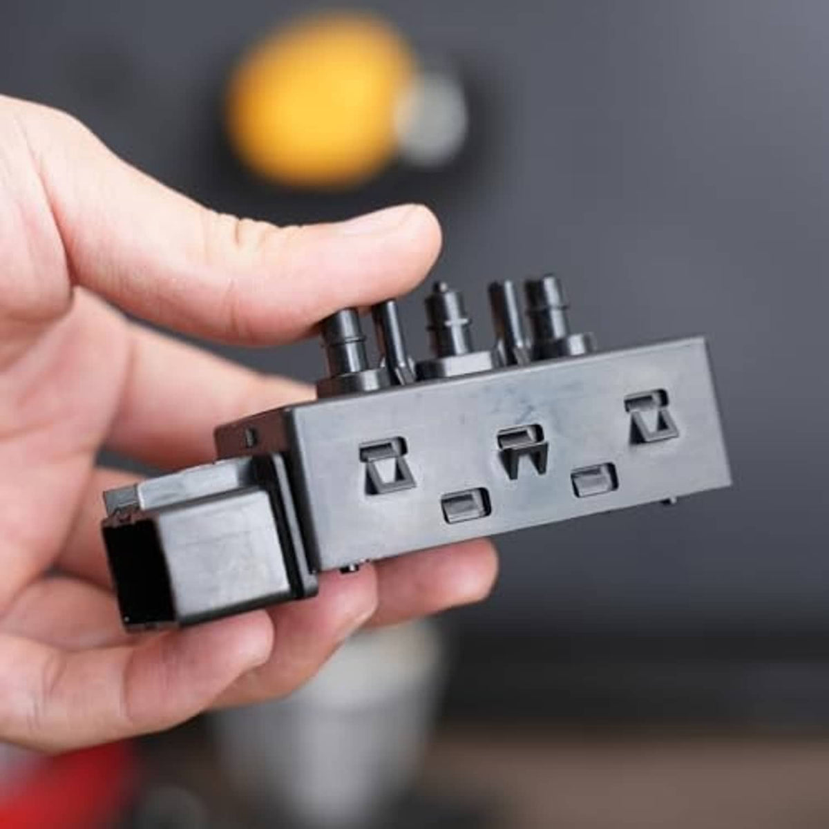 Power seat switch connector held in hand, showing front terminal openings