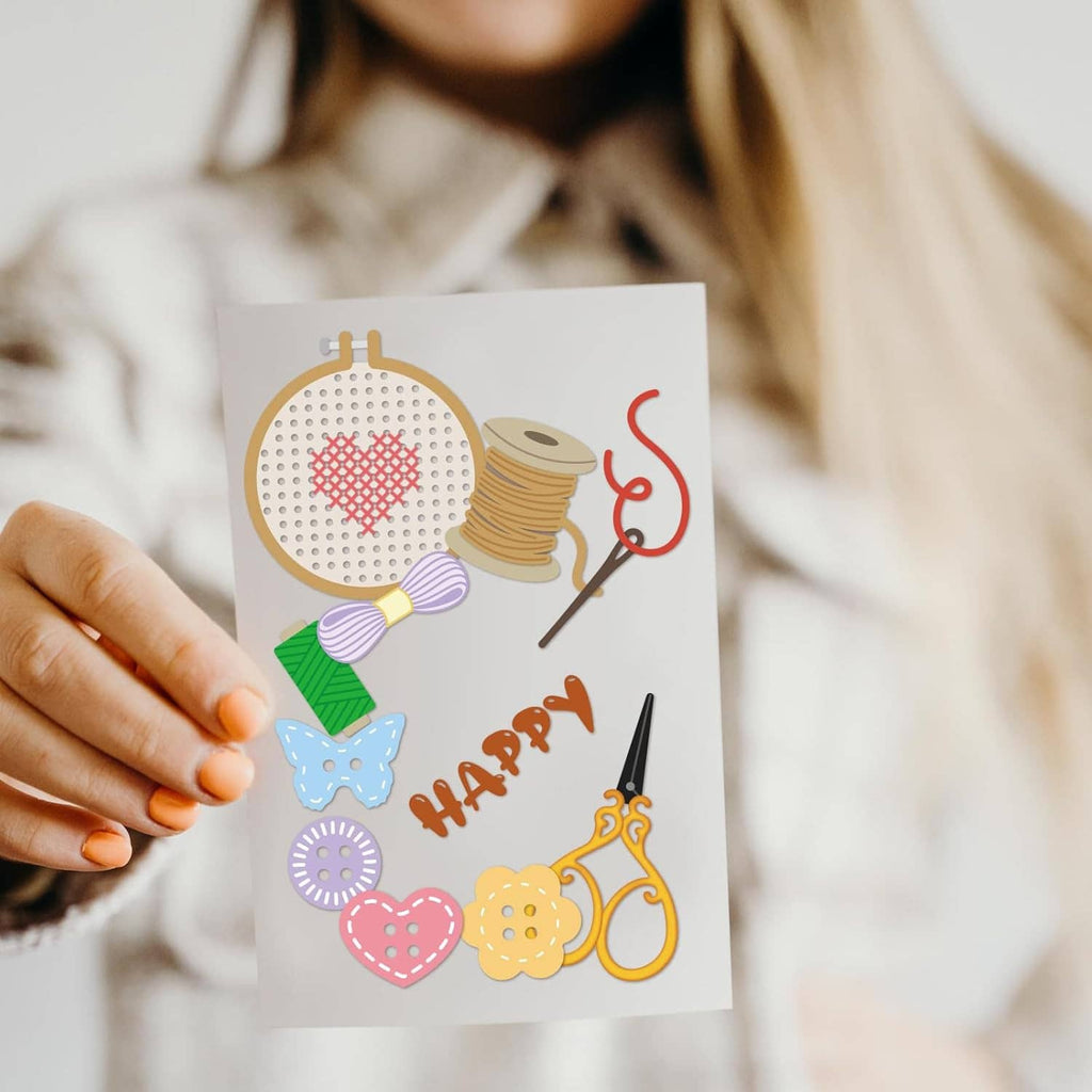 Sewing-themed card held in hand featuring embroidery hoop, thread spools, hearts, scissors