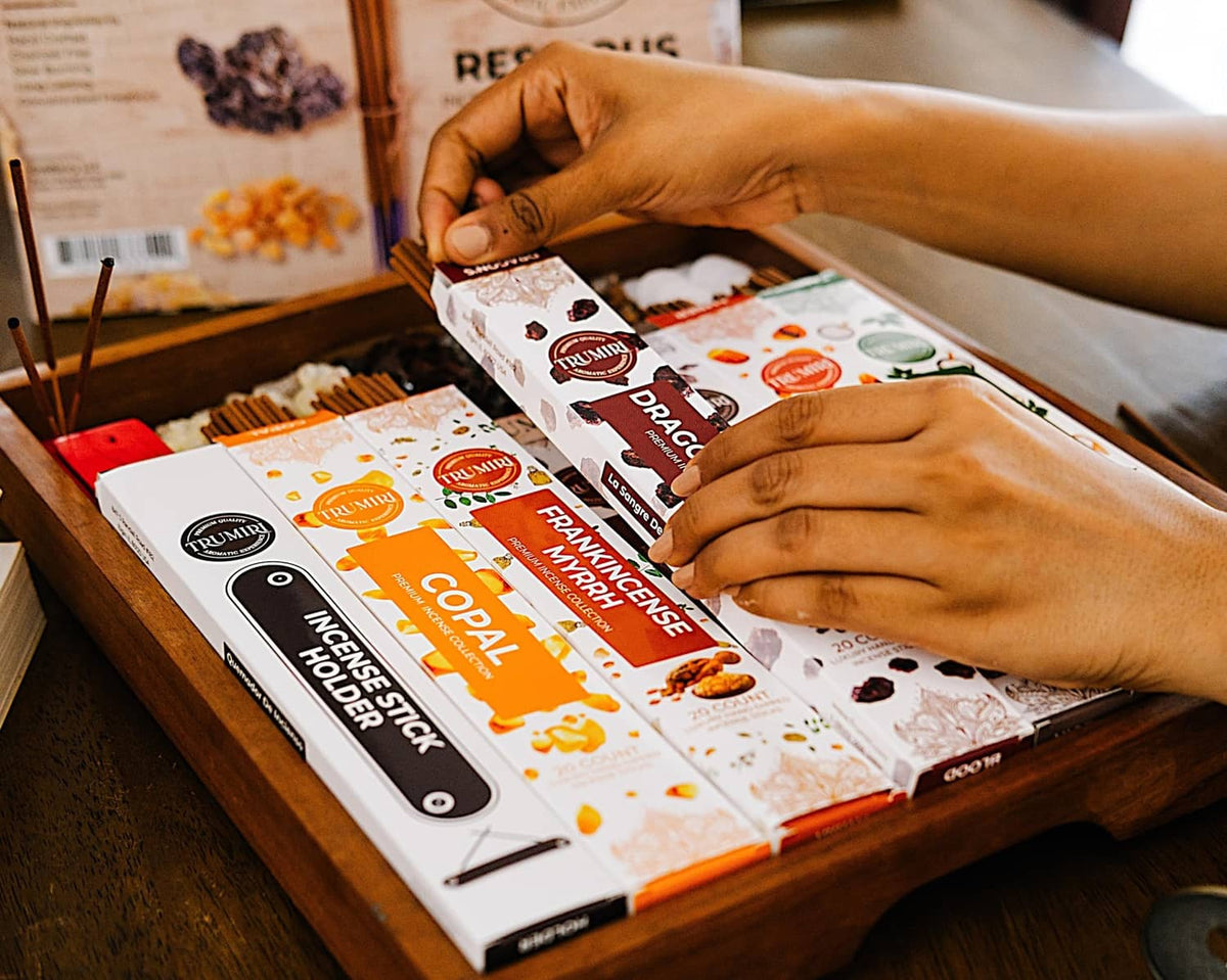 Trumiri incense stick box being opened by hands on a wooden surface