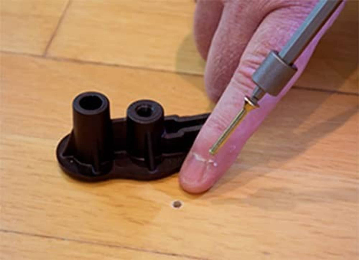 Black plastic snap base with metal screws and installation tip on hardwood floor