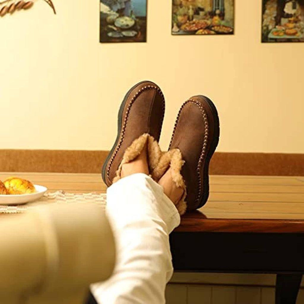 Pair of brown moccasin bootie slippers with tan faux-fur lining on feet