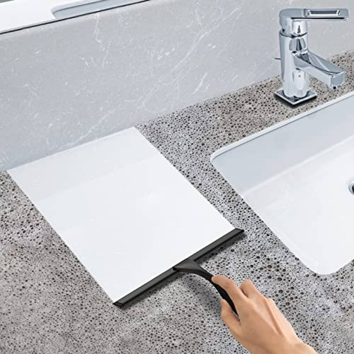 Black shower squeegee sliding across wet bathtub edge