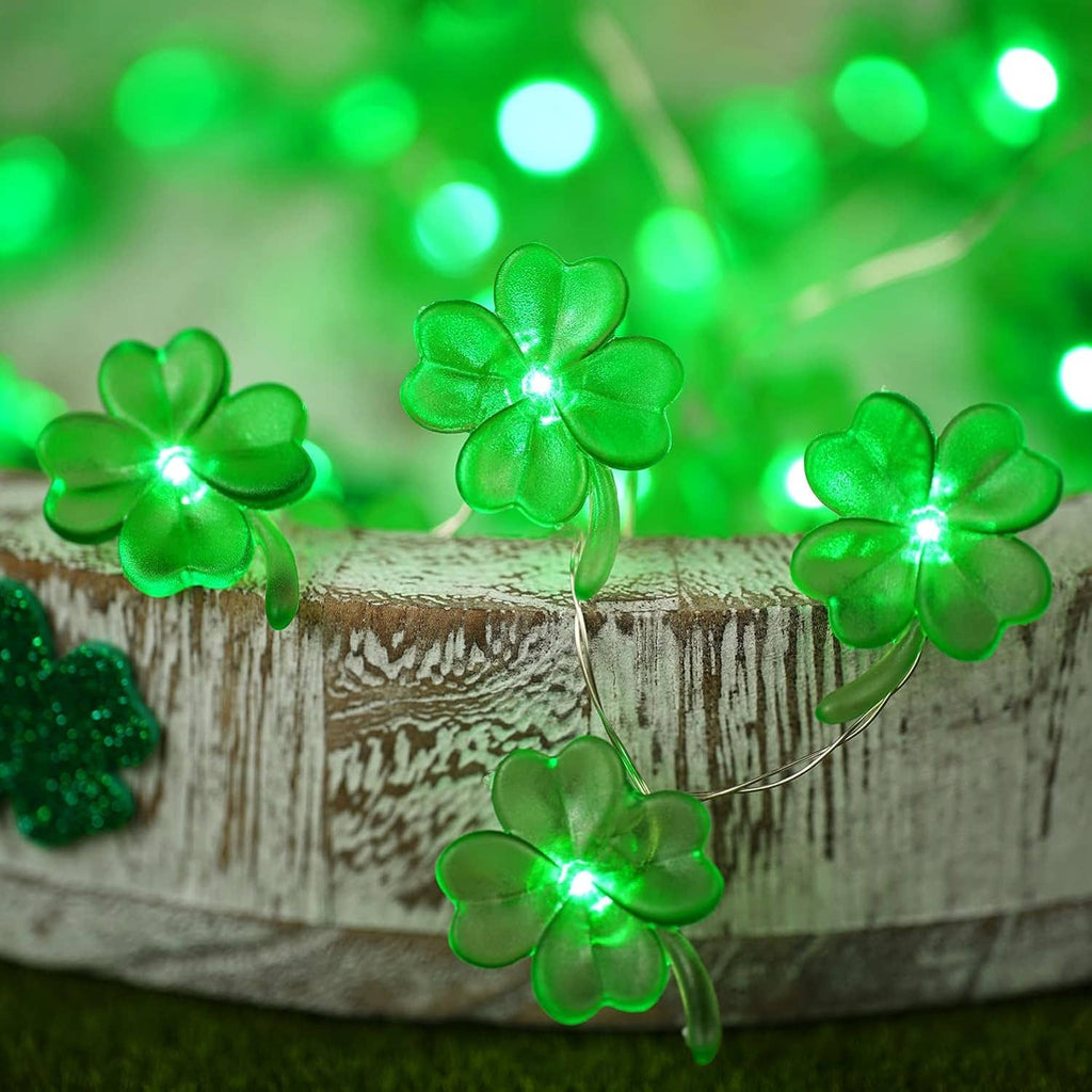 Green shamrock string lights glowing on a rustic wooden log with thin wire