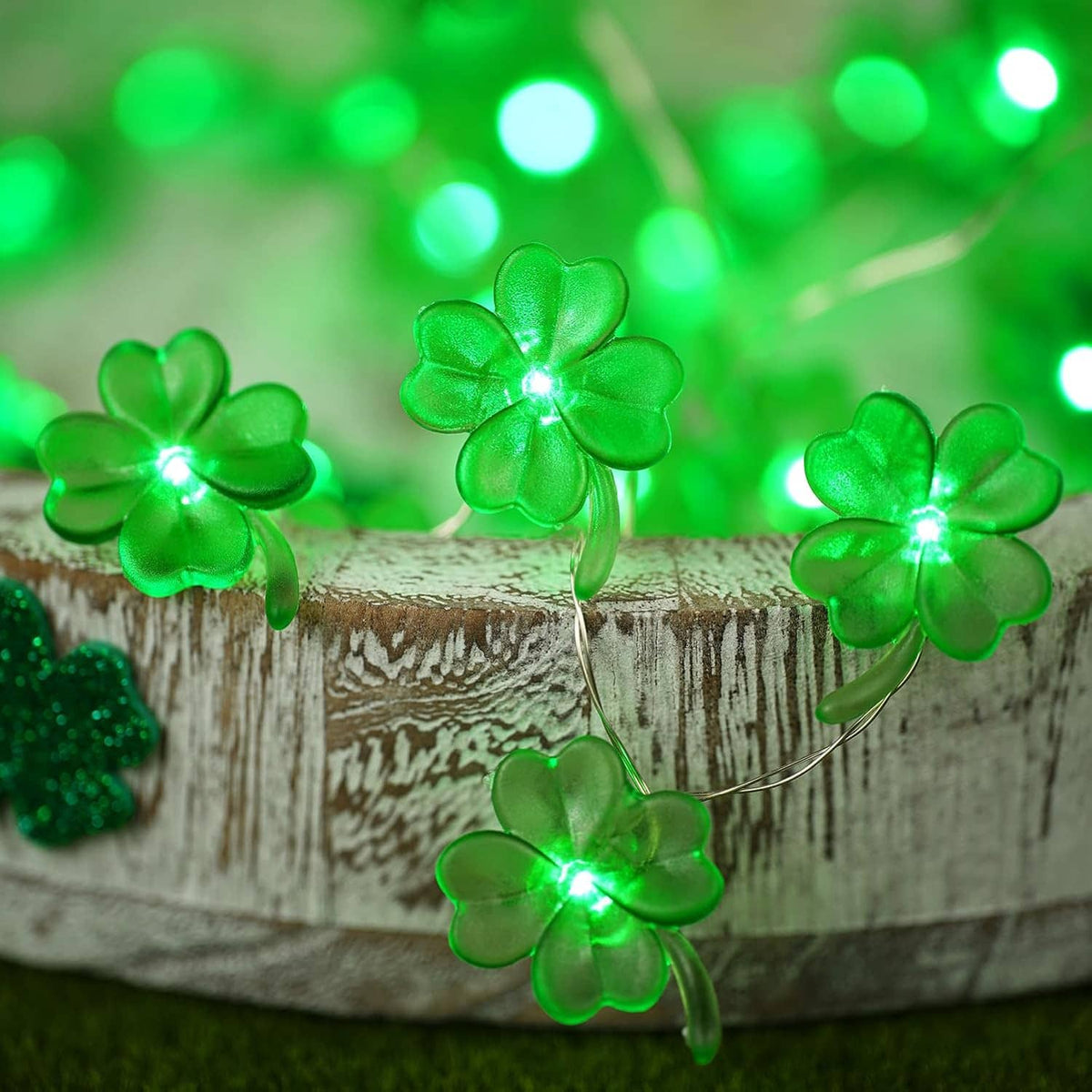 Green shamrock string lights glowing on a rustic wooden log with thin wire