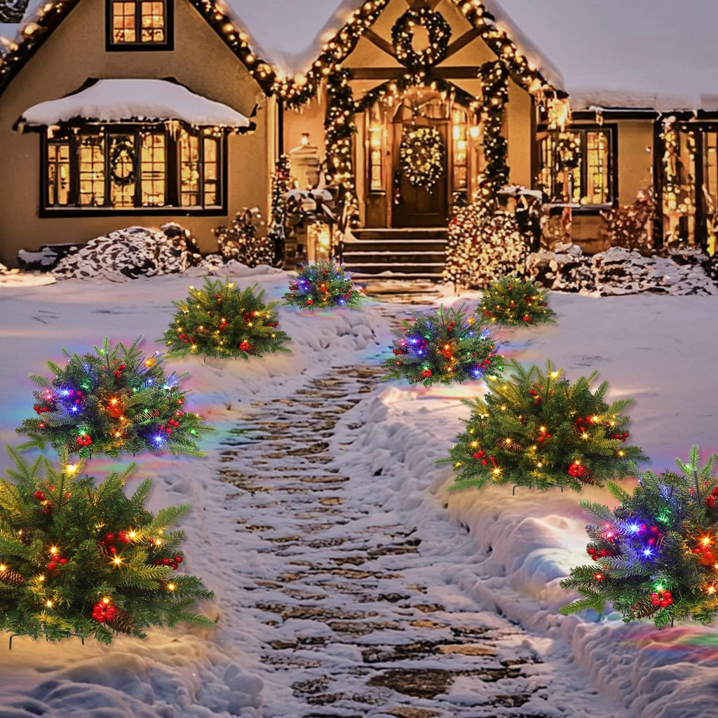 Set of pre-lit artificial Christmas trees with red berries and multicolor LED lights on walkway