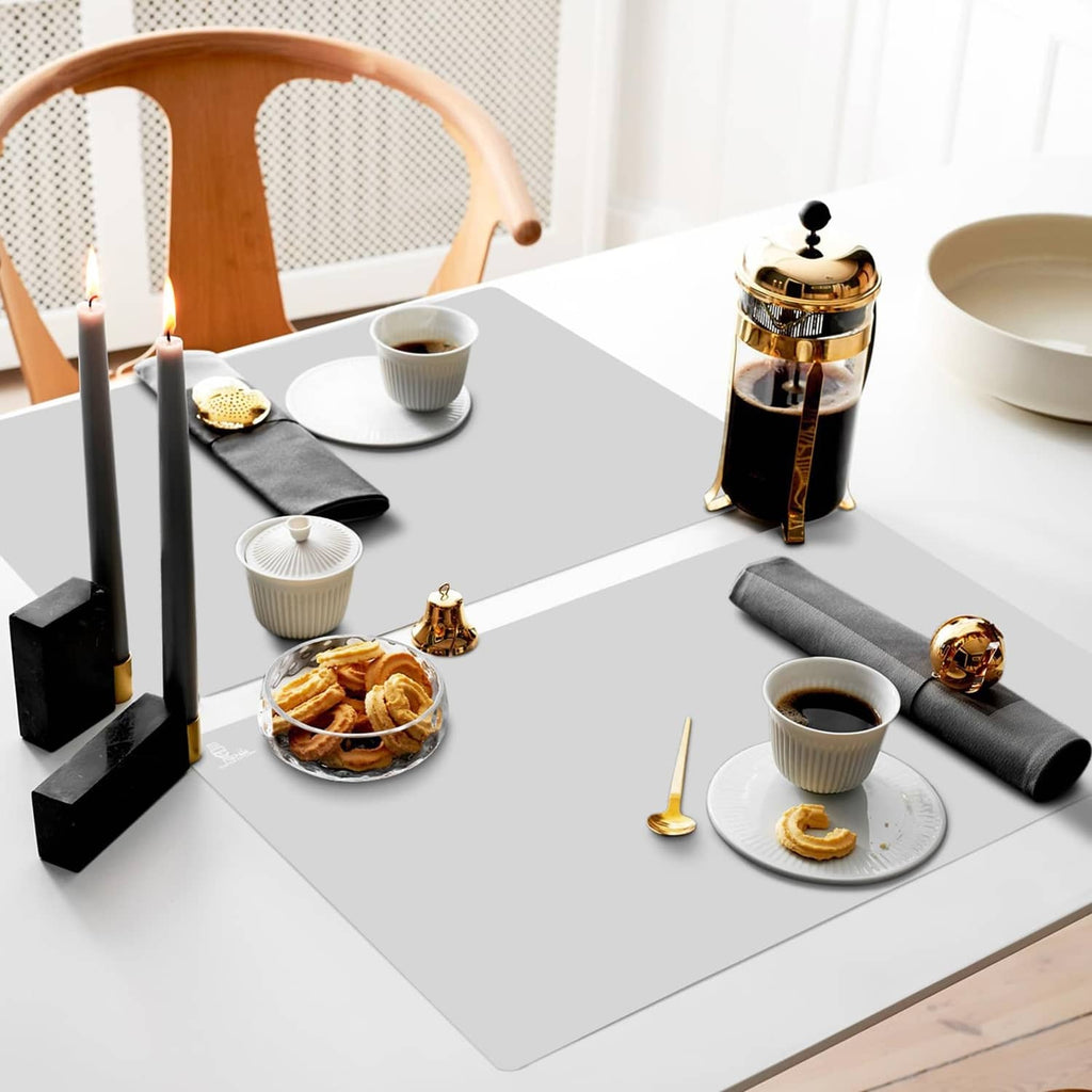 Gray silicone mat on tabletop with cups, teapot, and small snacks