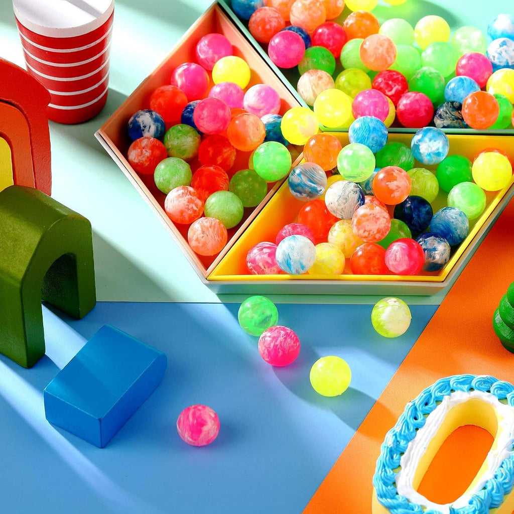 Small bouncy balls in an open gift box, mixed neon and marbled colors.