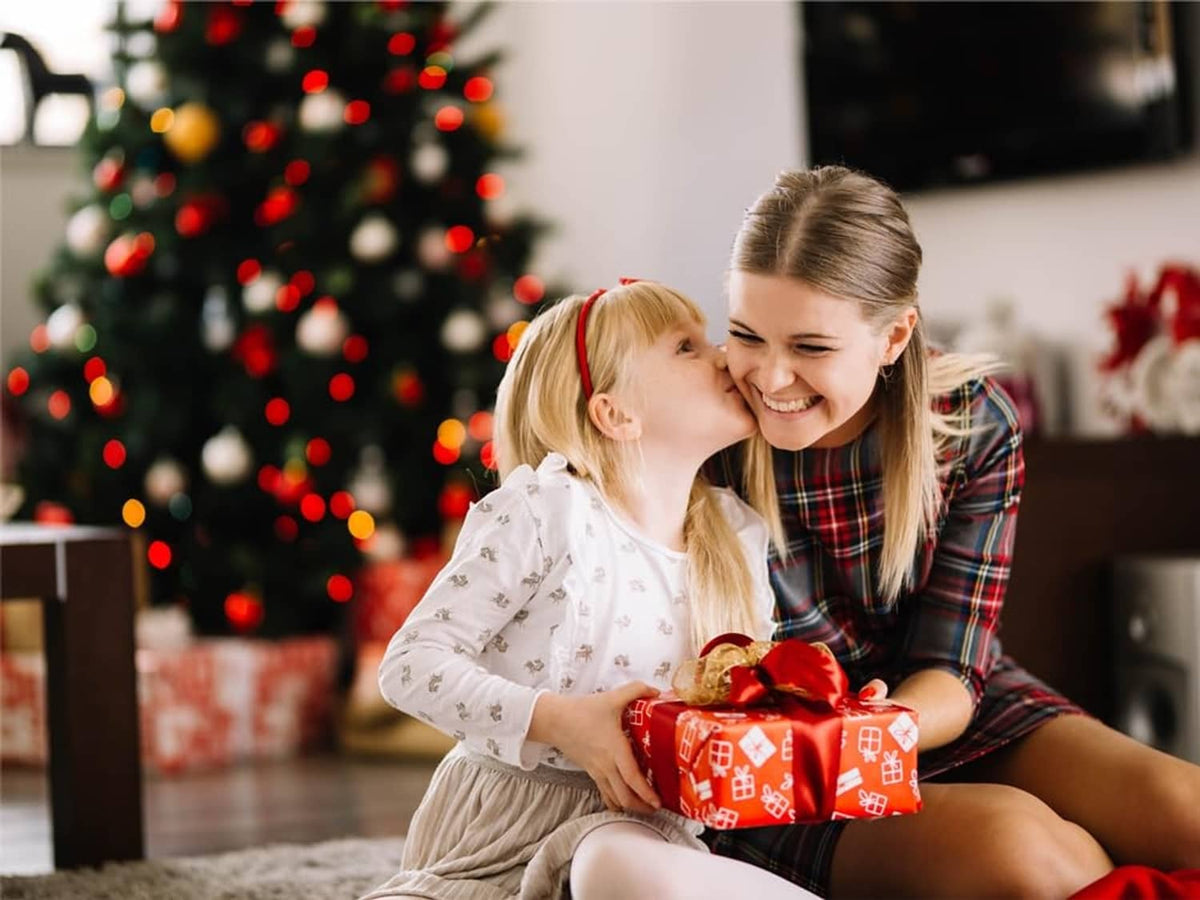 People holding yarn crafts and gifts near a decorated Christmas tree