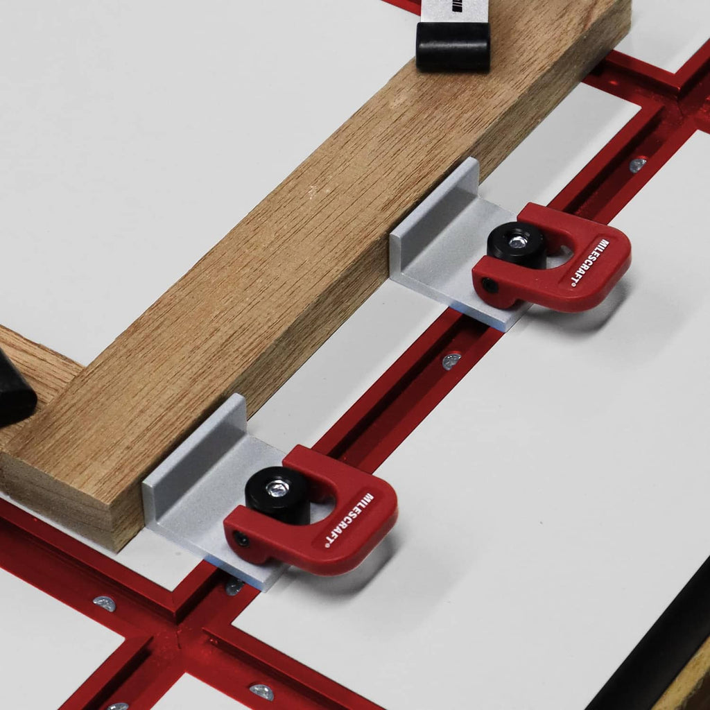 Red T-track cam stop clamps on a T-slot rail, securing a wooden workpiece