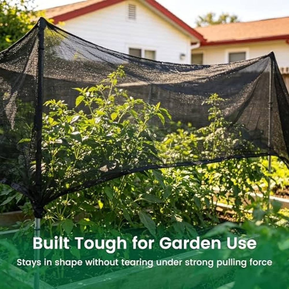 Black shade cloth draped over garden shrubs, held by cord and metal ties