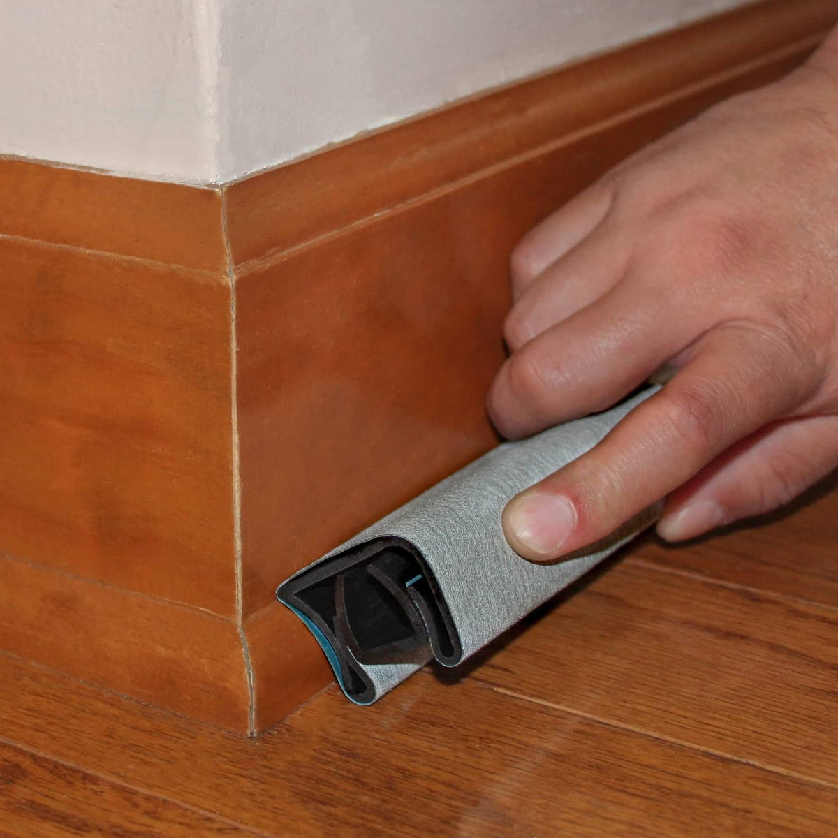 Milescraft Sand-It sanding block used on corner gap, gray abrasive sleeve in black holder