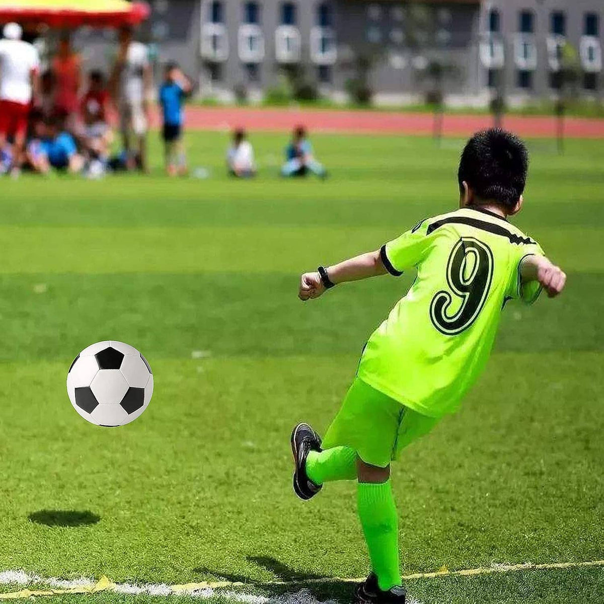 White and black soccer ball on the field near a running player