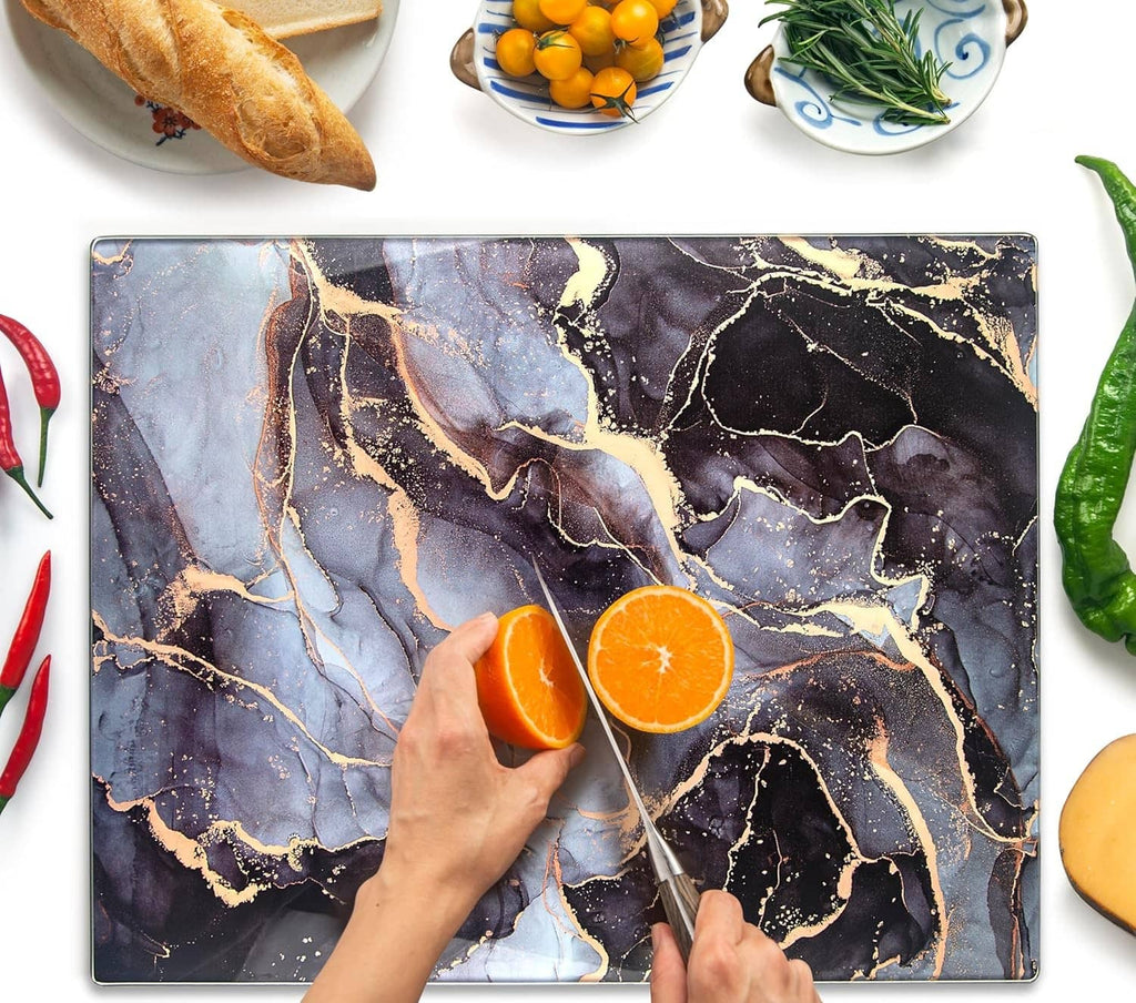 Tempered glass cutting board with blue and gold marbled pattern, hand slicing oranges
