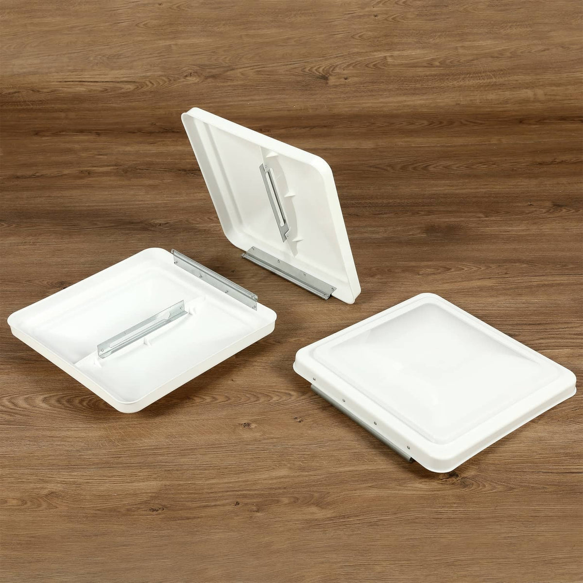 Three white RV roof vent covers, one open showing hinge and latching bar