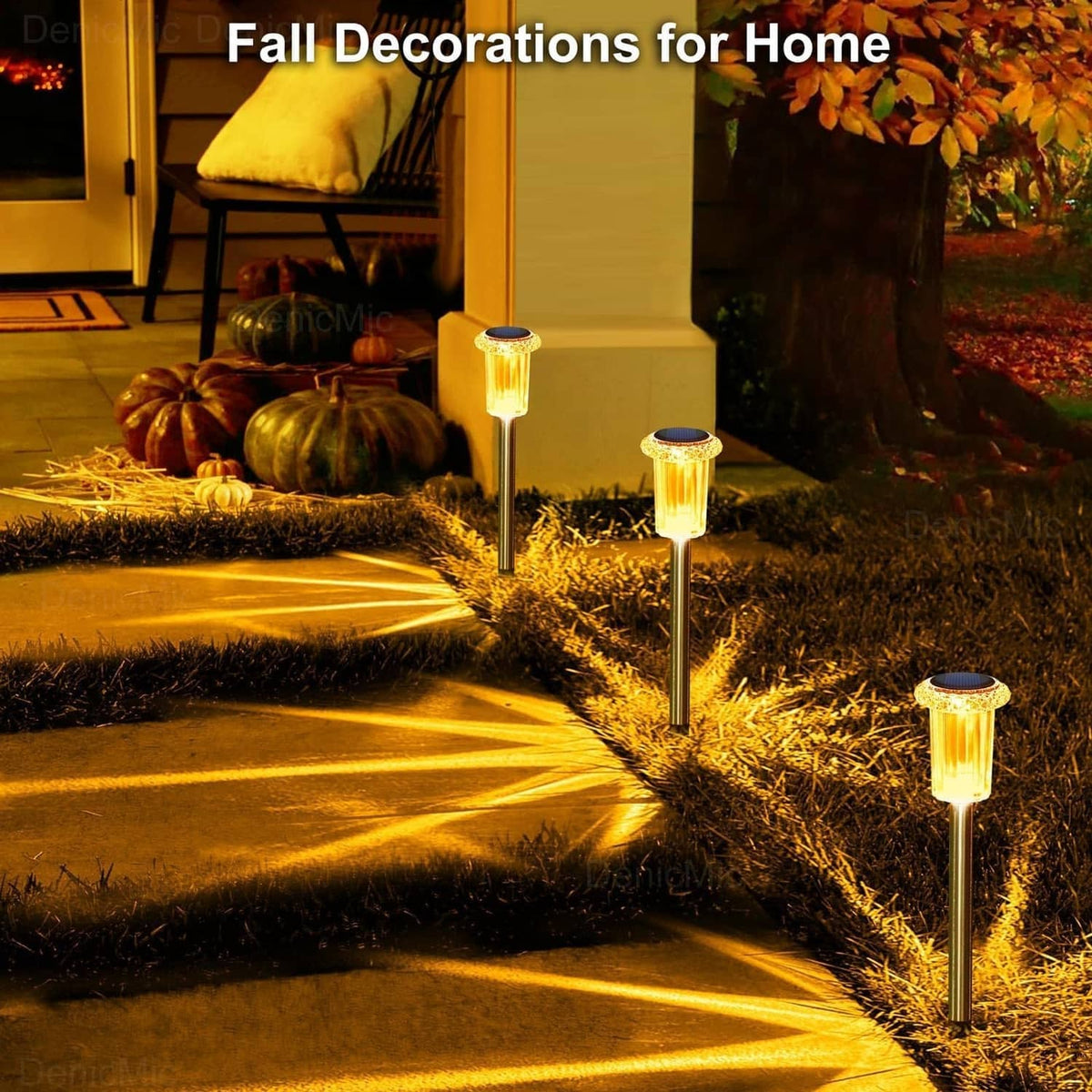 Amber solar spike lights along a yard path, illuminating grass with starburst glow