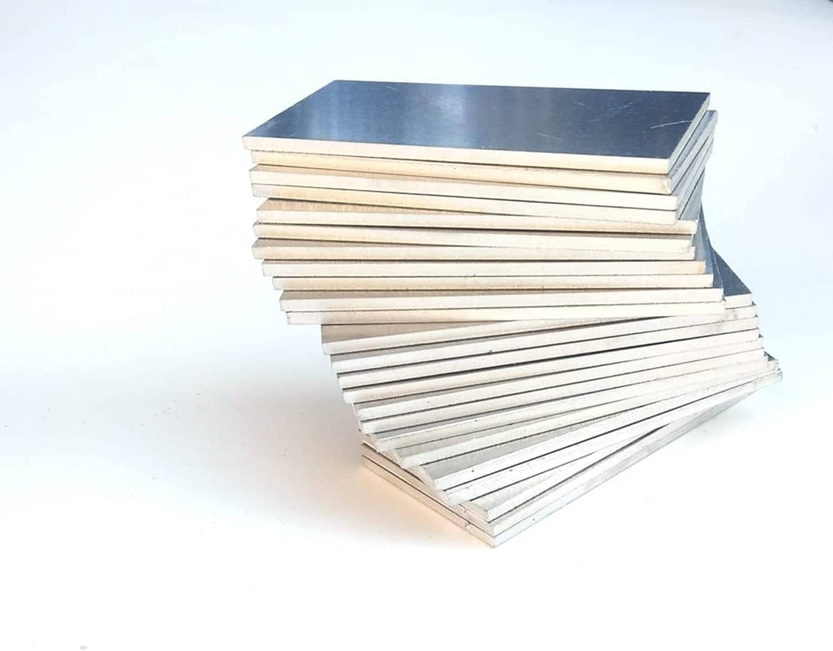Pile of silver aluminum practice coupon plates, rectangular sheets stacked at a diagonal.