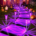 Purple solar pathway spike lights with glowing starburst pattern in a lawn garden