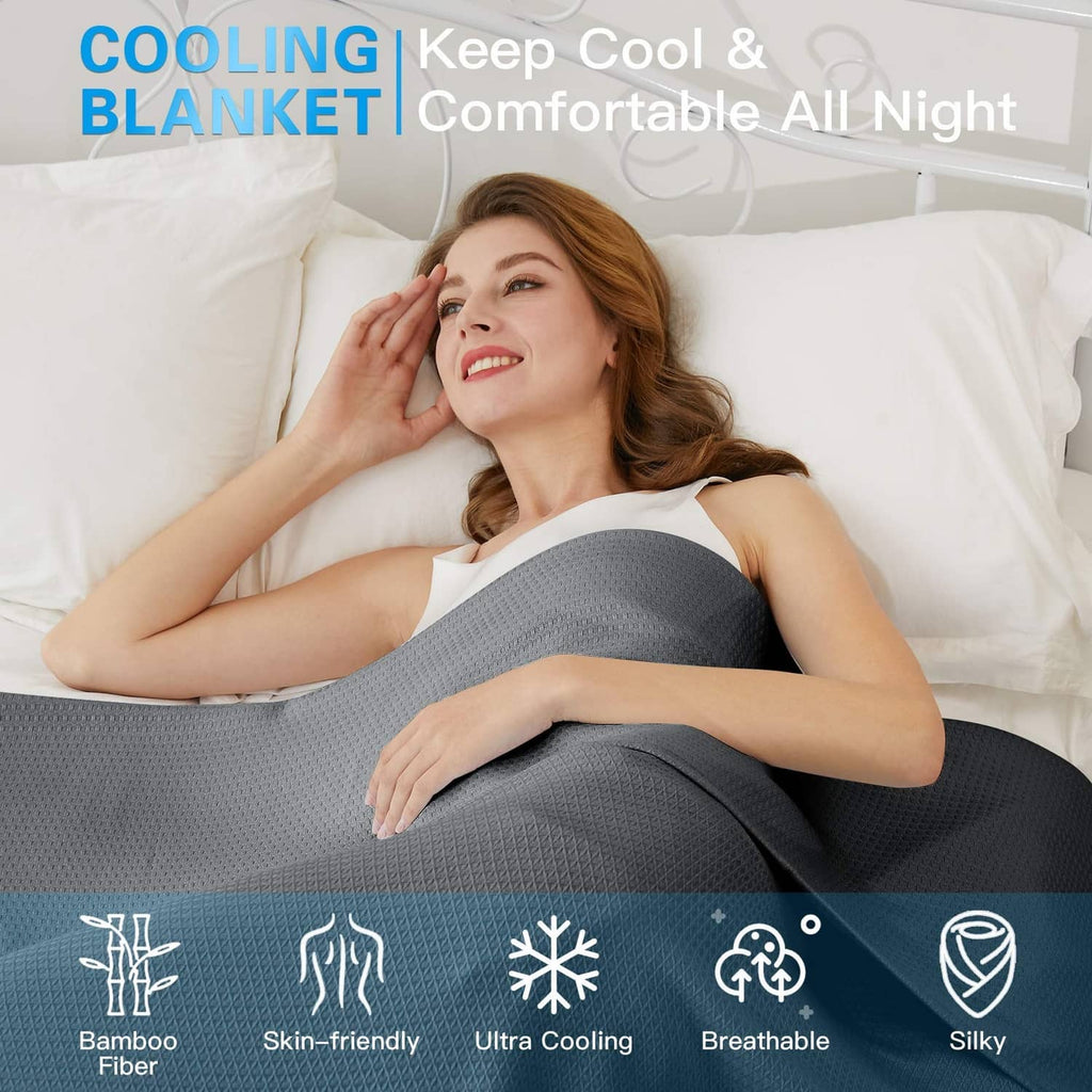 Dark gray cooling blanket wrapped around a person on a white bed
