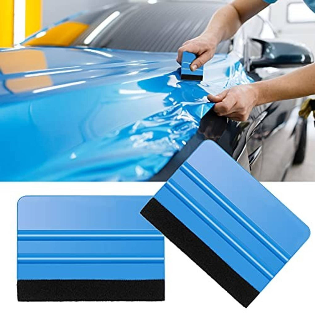 Hands using a blue felt-edge squeegee to smooth a large vinyl film on a car