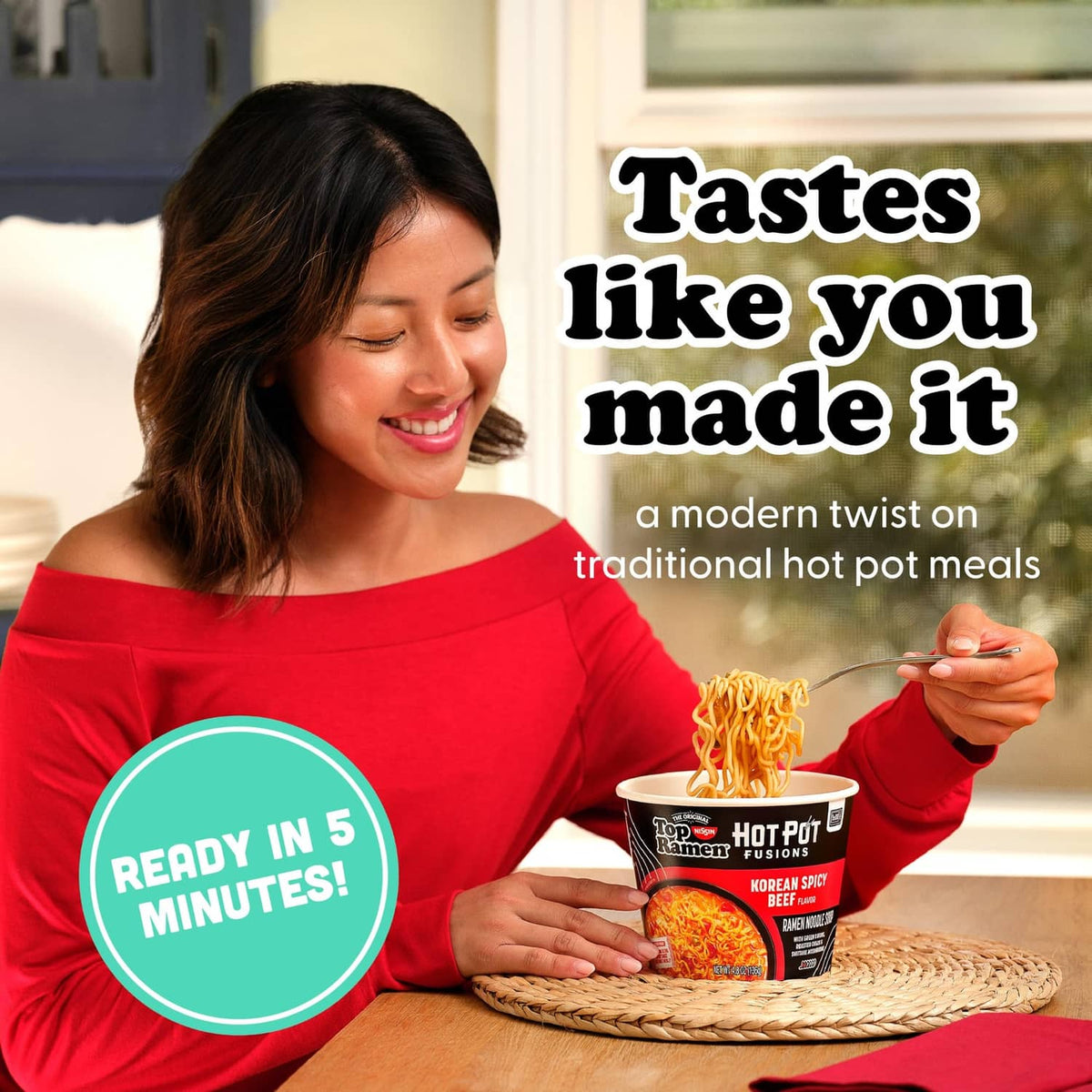 Ramen hot pot cup with Korean spicy beef noodles, held above a table by a person