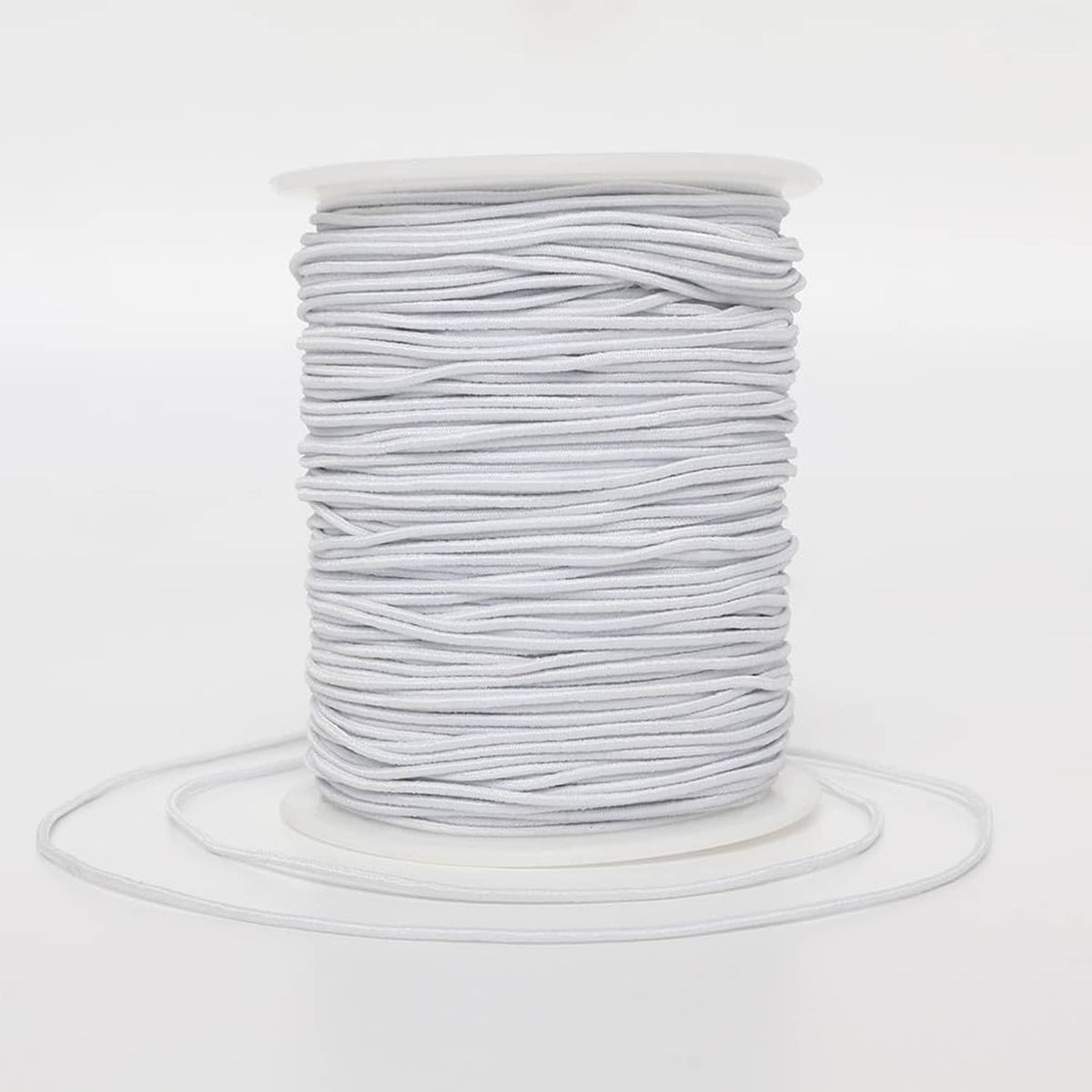 White elastic string spool, thin cord wound on a plastic bobbin