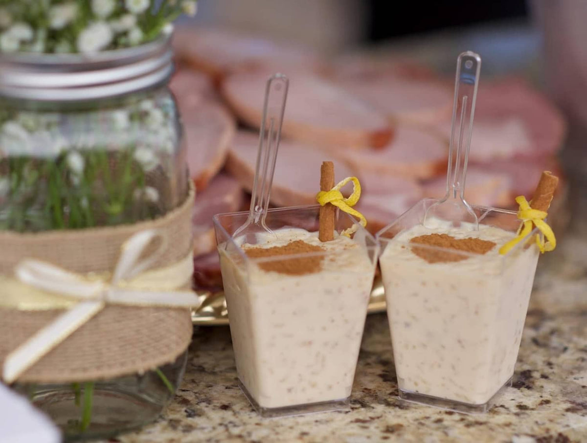 Clear square plastic dessert cups with tall plastic spoons, filled with dessert