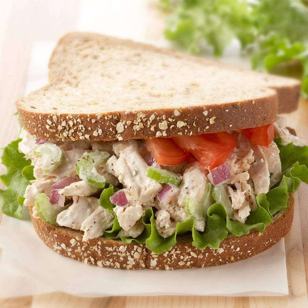 Sandwich filled with chopped chicken, lettuce, and celery garnish
