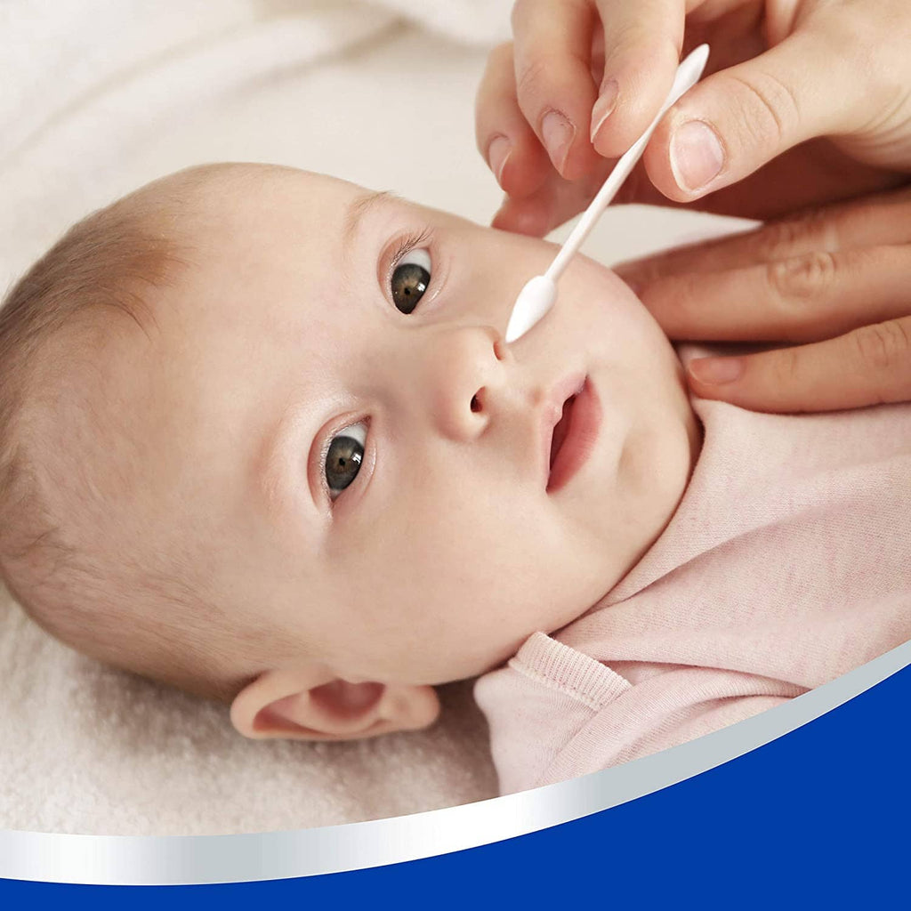 Baby lying down while a cotton swab is used near the face