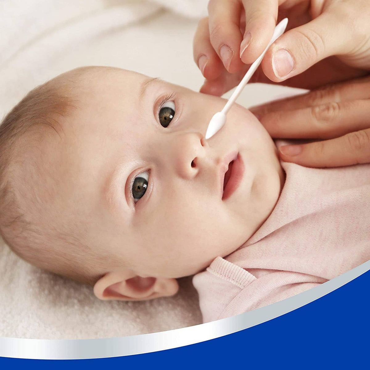 Baby lying down while a cotton swab is used near the face