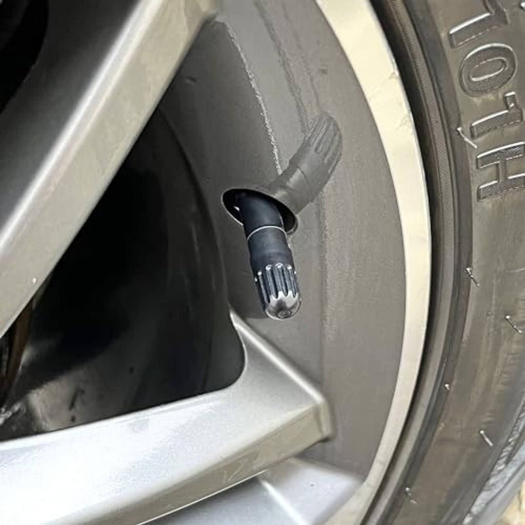 Black long tire valve stem cap installed on a car wheel valve