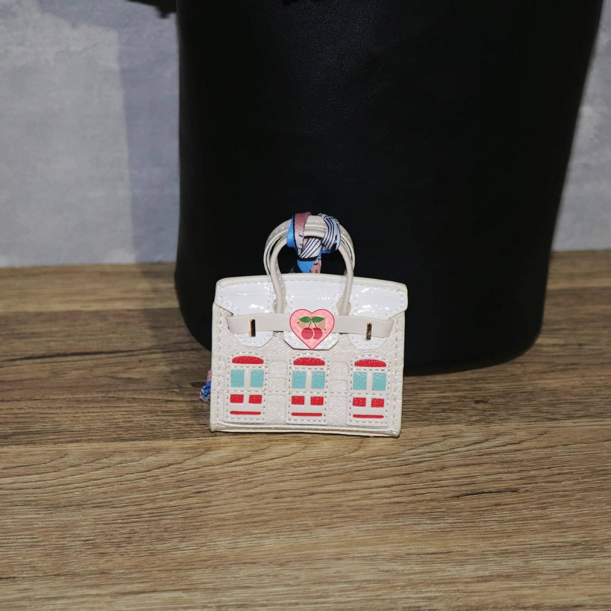 White mini backpack keychain pouch with heart tag and red/green window print.