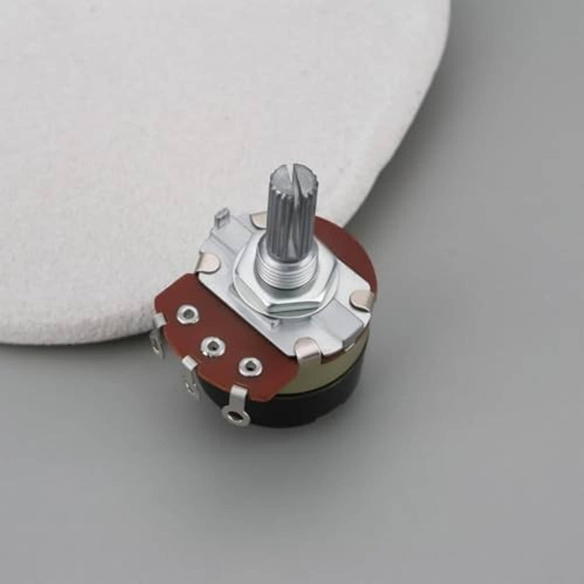 Rotary potentiometer top view with knurled metal shaft and red-brown contact area