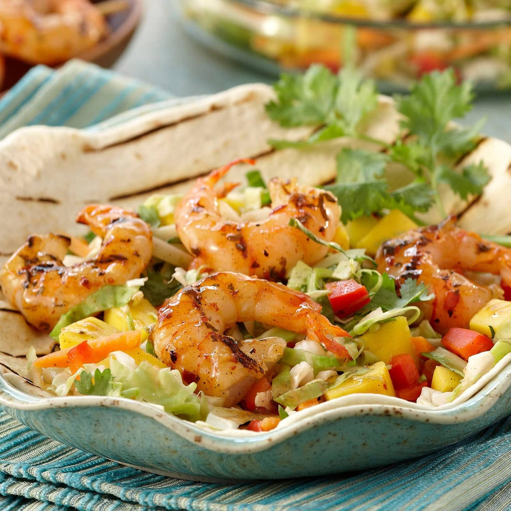 Opened taco shells filled with shrimp-like filling, pico de gallo, and cilantro