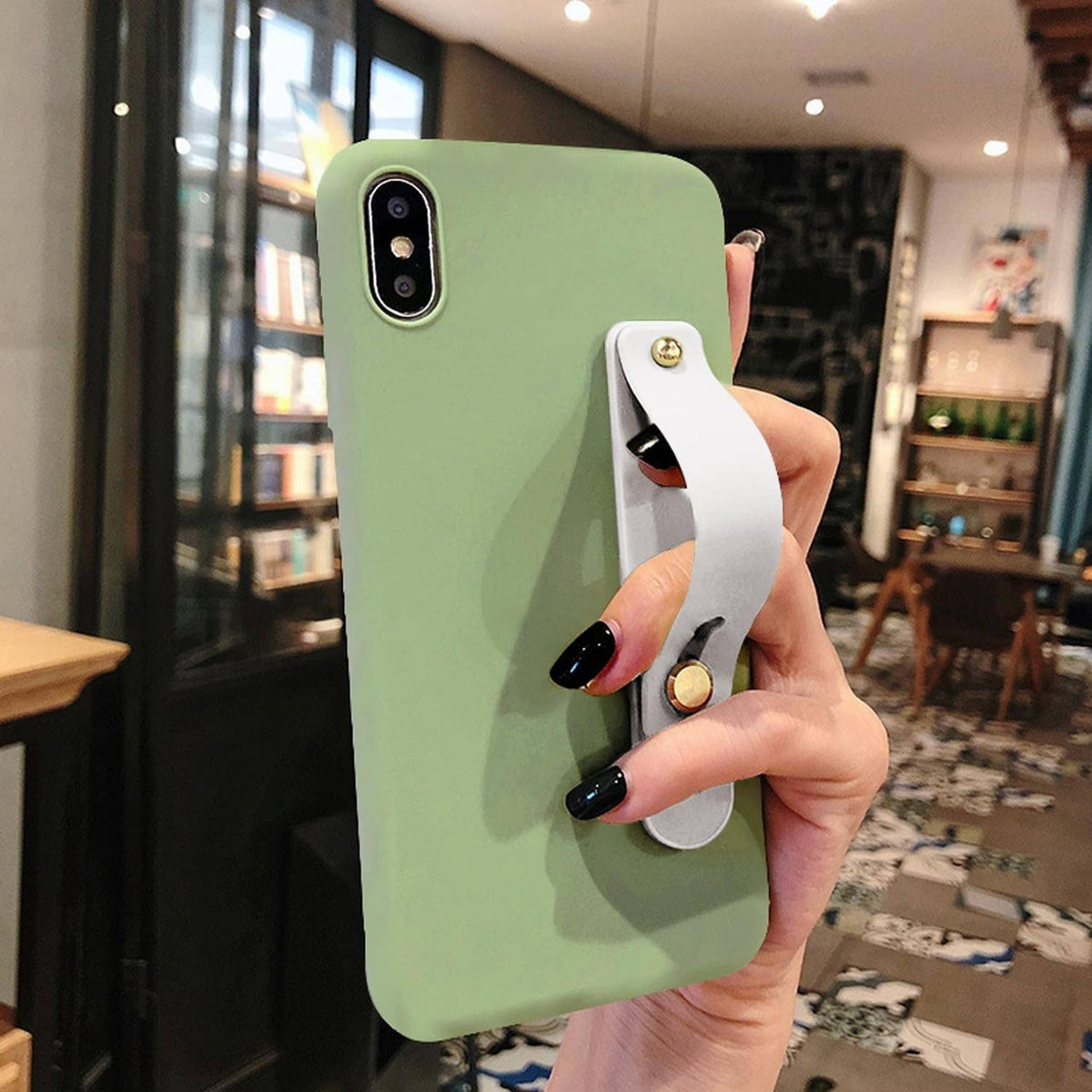 Green phone in hand with white finger strap holder and gold circular accent