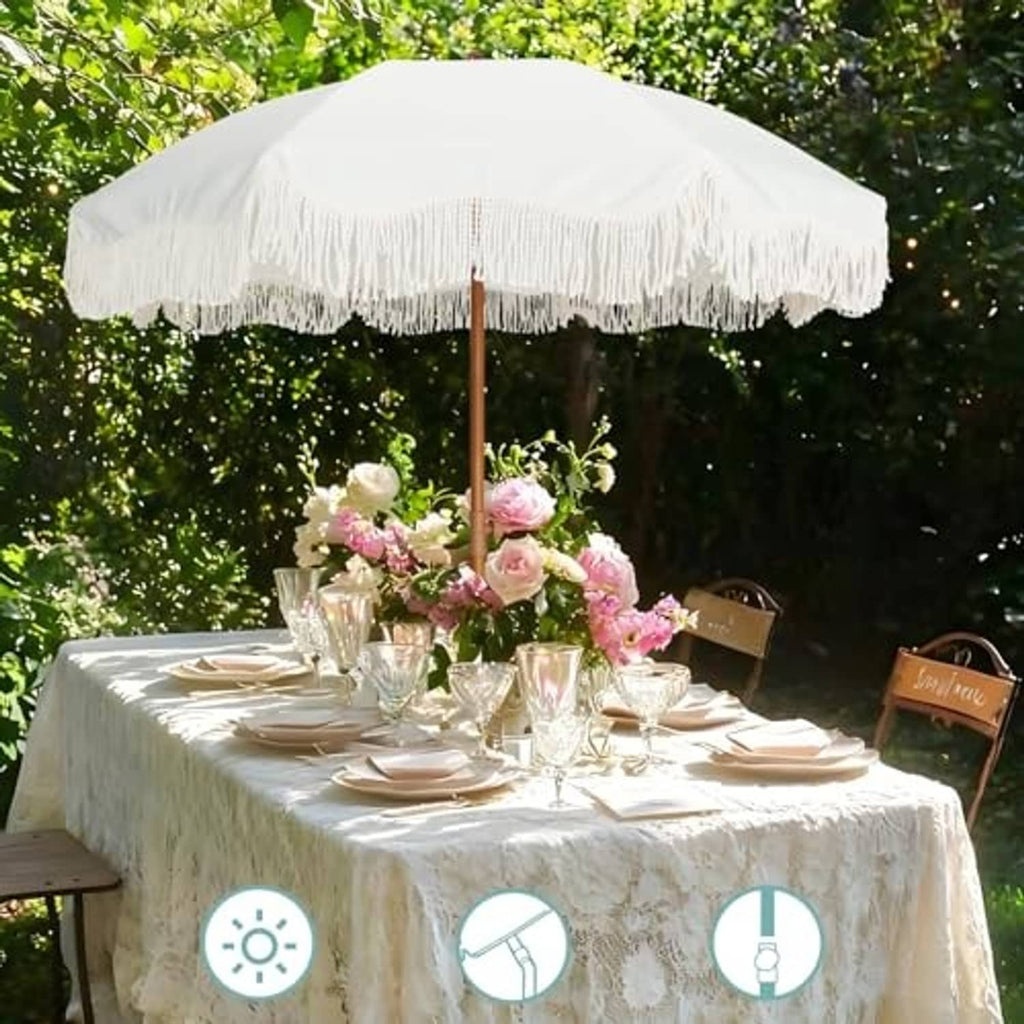 Outdoor patio umbrella over a table with white fringe canopy and wooden center pole.