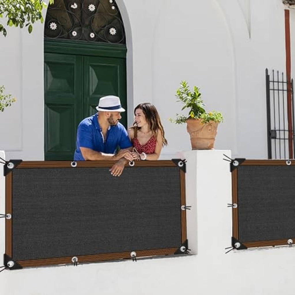 Two black shade cloth panels with brown edging and metal grommets, mounted outdoors