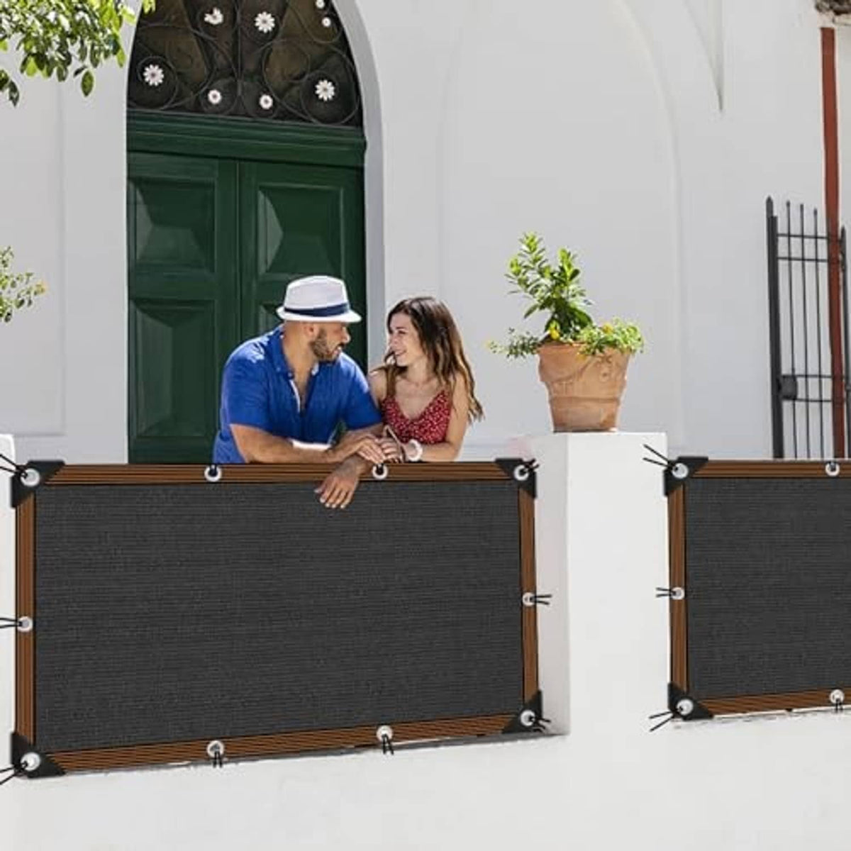 Two black shade cloth panels with brown edging and metal grommets, mounted outdoors