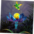 Solar wind spinner with green hummingbird on blue-purple flower, glowing yellow LED orb