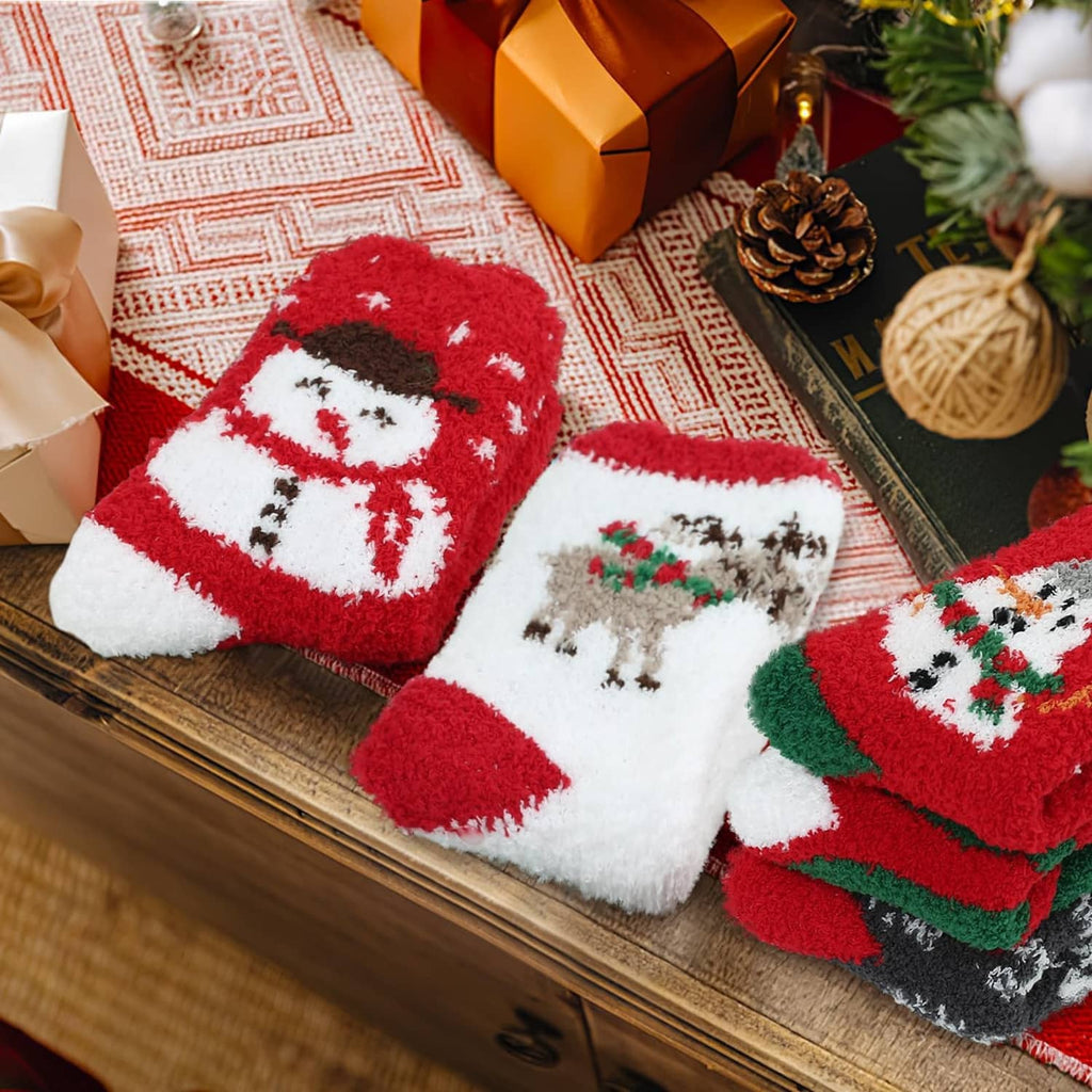 Christmas crew socks with bold snowman face design in red, green, and white, laid on a wooden surface
