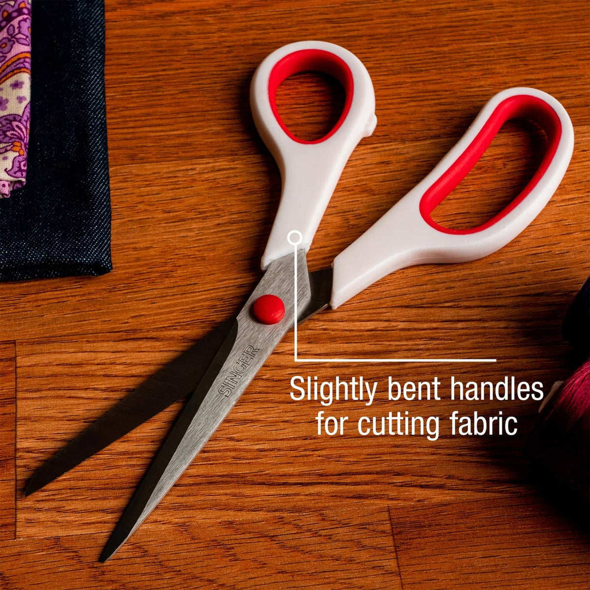 Red-and-white handled fabric scissors with slightly bent handles and pointed tips