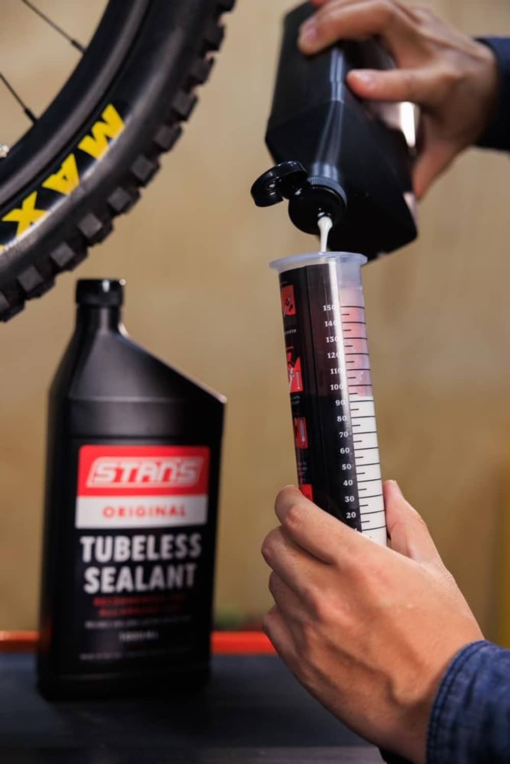 Person using tubeless sealant injector with syringe scale to measure sealant