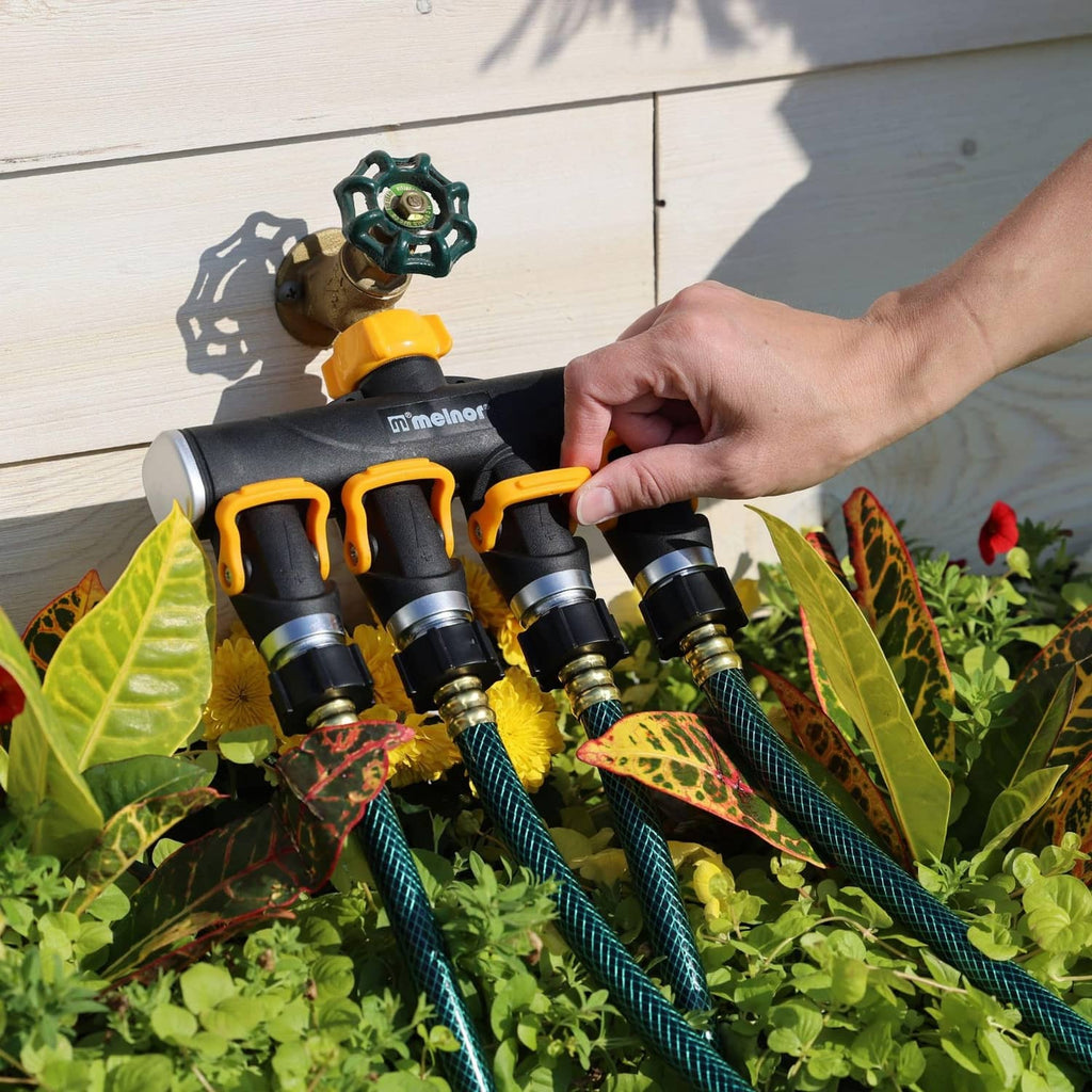 Hand turning yellow levers on a 4-way valve splitter with blue hose connections