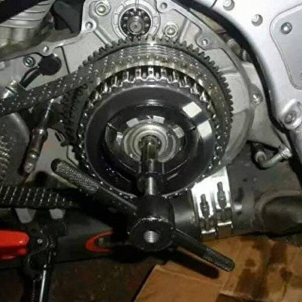 Spring compressor tool positioned on engine near gears and clutch area, close-up detail