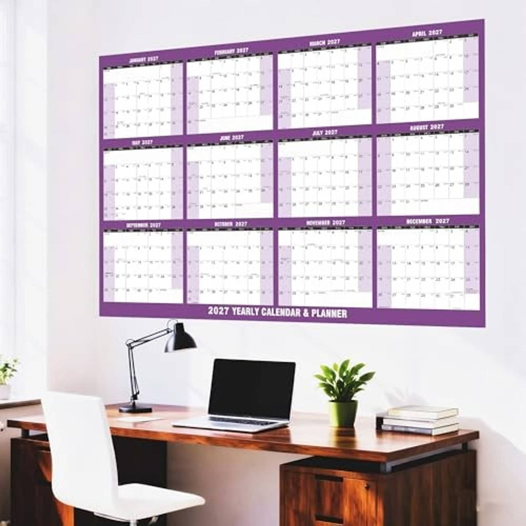 Purple 2027 wall calendar planner mounted above a desk with lamp and books