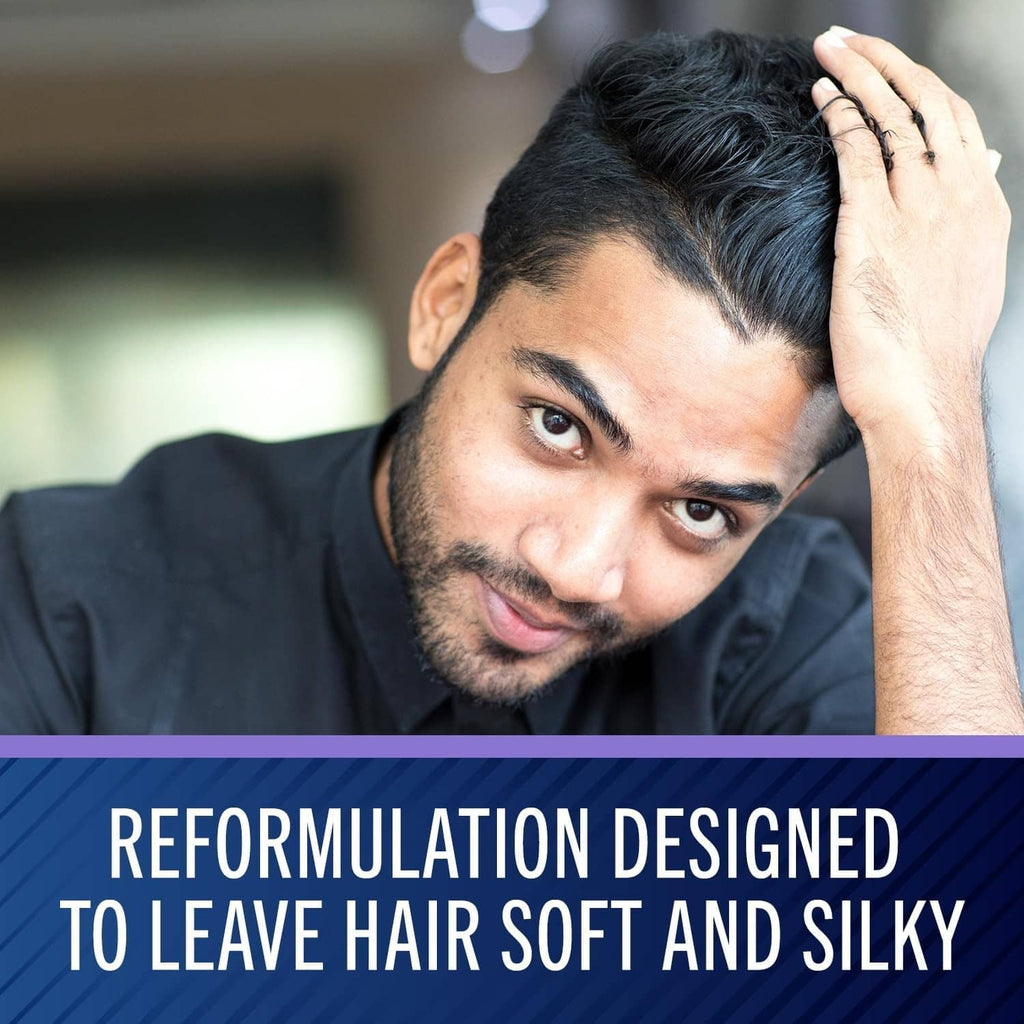 Man with dark hair touching his scalp with one hand
