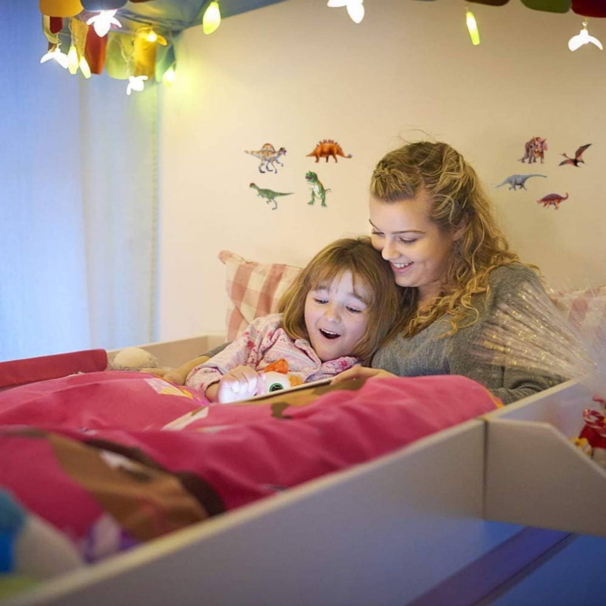Dinosaur wall stickers on living room wall behind a smiling child and caregiver