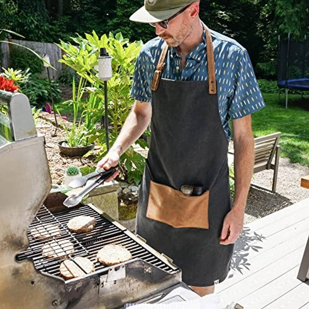 Men's dark charcoal apron with tan faux leather straps and front utility pocket