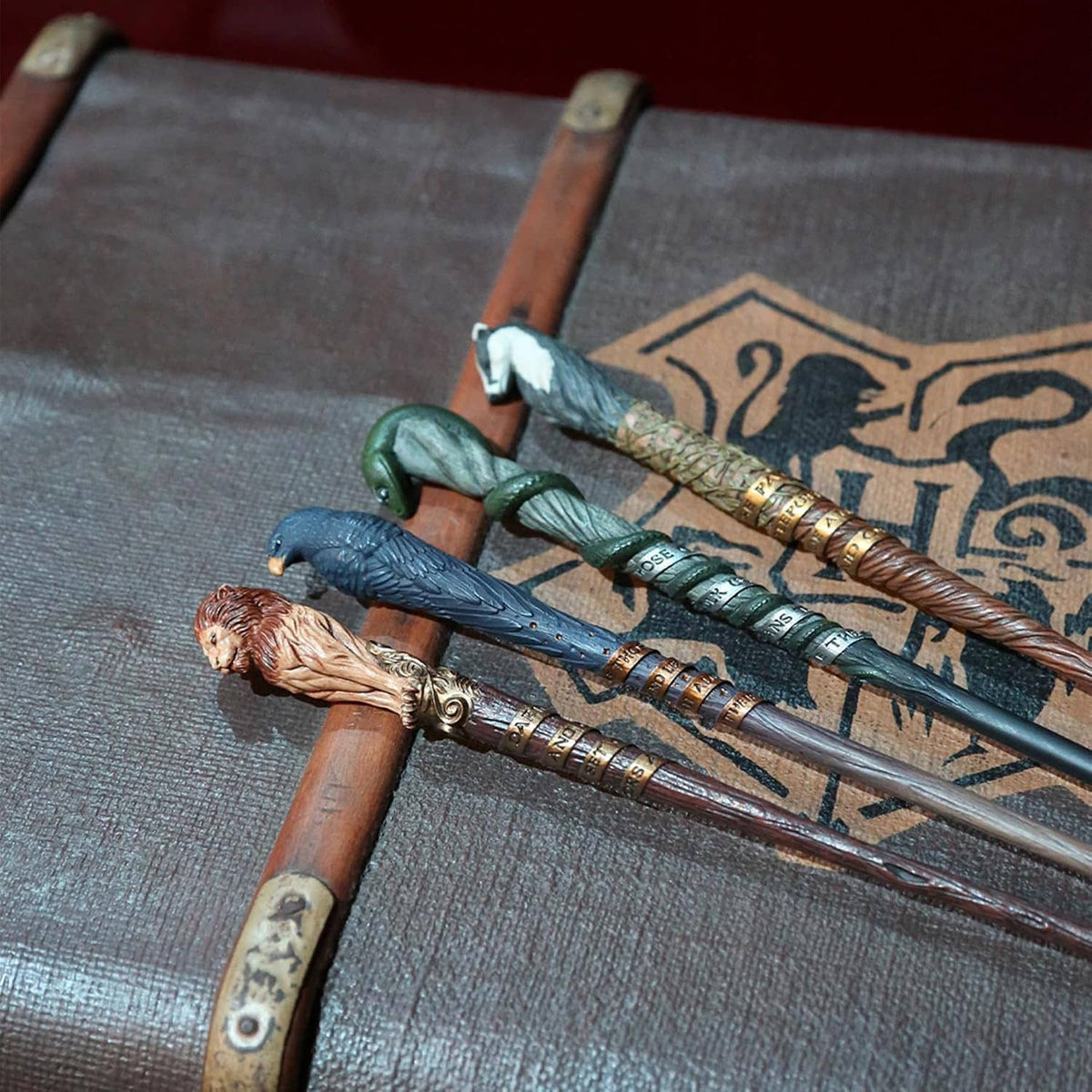 Multiple engraved collectible wands laid across a fantasy-patterned book cover