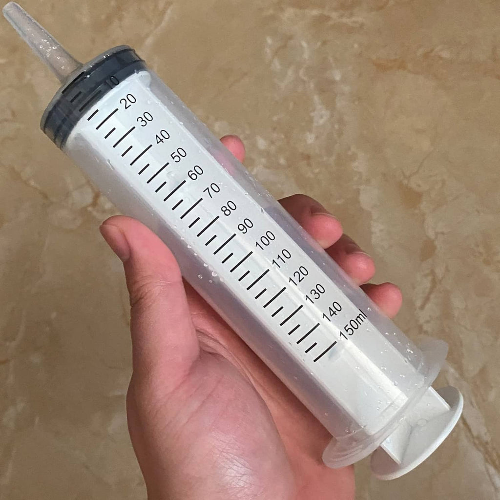 Handheld clear 150 ml syringe with black cap and black measurement markings
